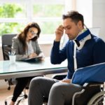 A frustrated patient in a wheelchair and arm sling tries to make sense of a medical bill, highlighting the importance of claim editing