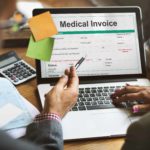 People review managed care reimbursement with a medical invoice pulled up on a laptop