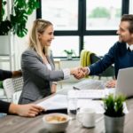 As they enjoy the advantages of TPAs in health insurance, a man and woman shake hands with their third-party administrator over completed paperwork.